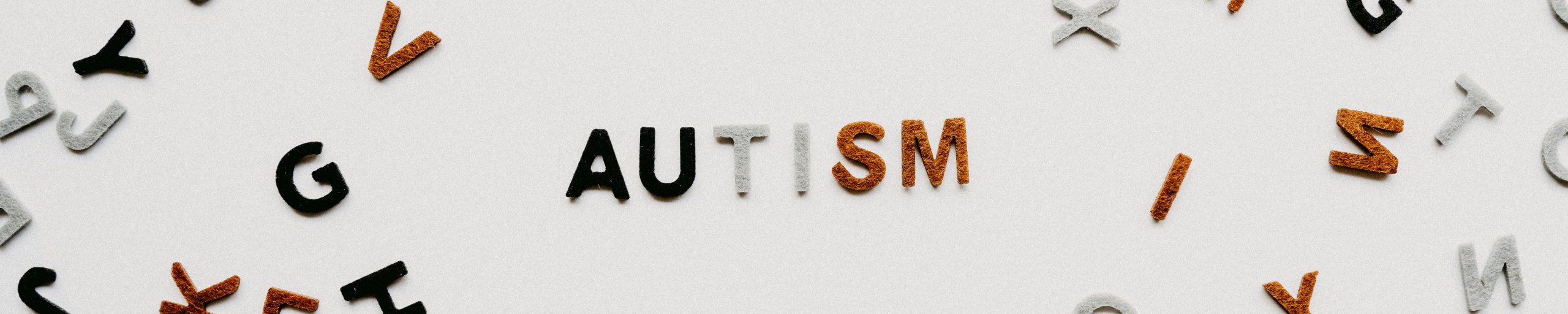 Photo of colorful letters lined up to form 'Autism' word, surrounded by scattered letters