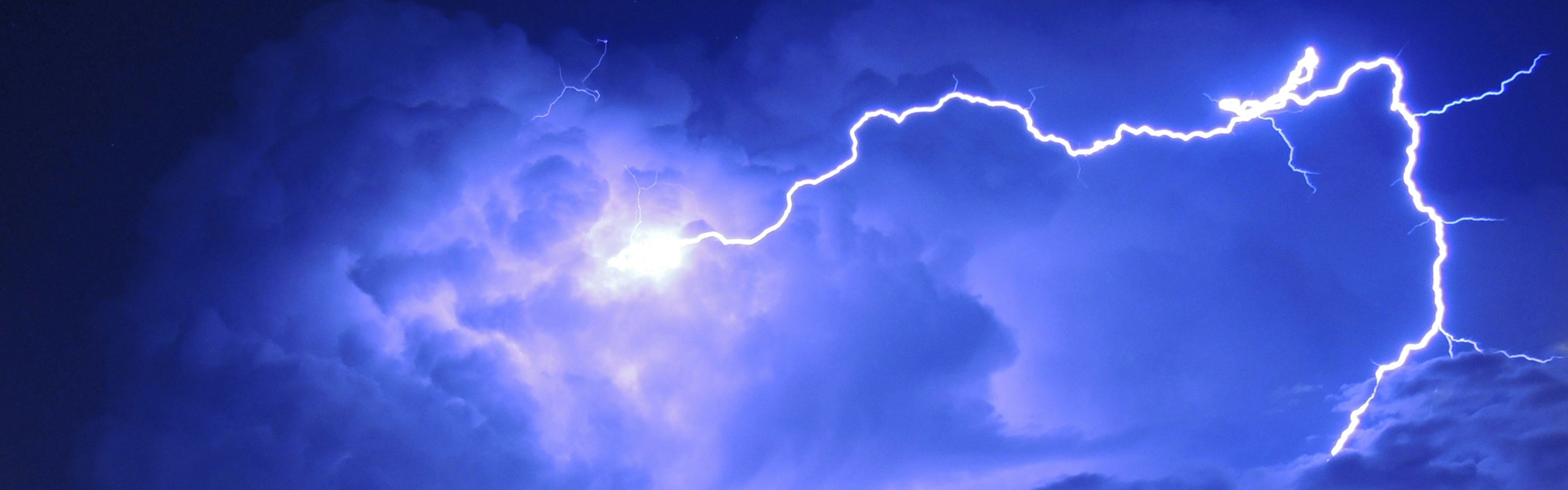 Photo of a night sky lit up by lightning, giving it a deep violet hue