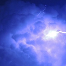 Photo of a night sky lit up by lightning, giving it a deep violet hue