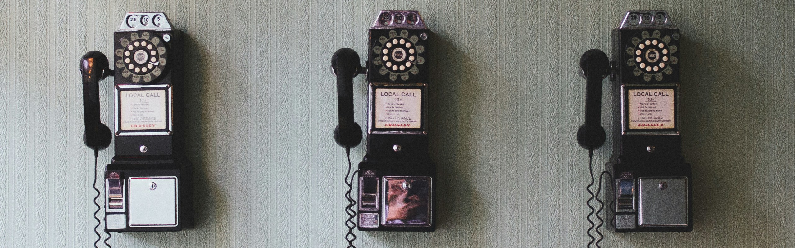 Photo of three vintage telephones on a wall